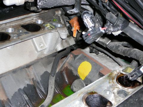 1997 Mercury Grand Marquis - Close-up inside a stripped V8 engine valley with the intake removed, showing green coolant residue, a yellow paint mark on the block and a…