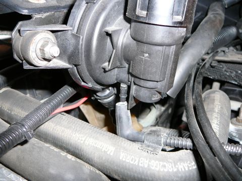 1997 Mercury Grand Marquis - Tight engine-bay close-up of a black plastic sensor/actuator housing on its bracket with the DPFE unit unbolted, showing the freed nipple,…