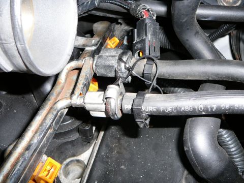 1997 Mercury Grand Marquis - Close-up of a fuel rail and high-pressure fuel line connections in an engine bay, showing metal fuel lines, quick-disconnect fittings, and…