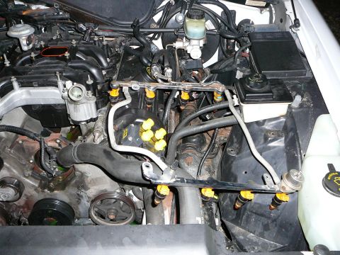 1997 Mercury Grand Marquis - Engine bay with the intake manifold removed, leaving the fuel rails still bolted in place with eight yellow-topped injectors hanging free o…