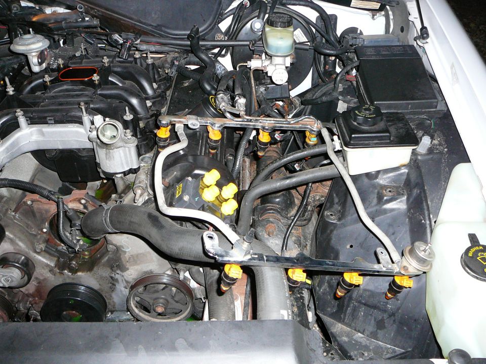 Fuel rails with yellow-topped injectors left in place over a disassembled V8 engine bay
