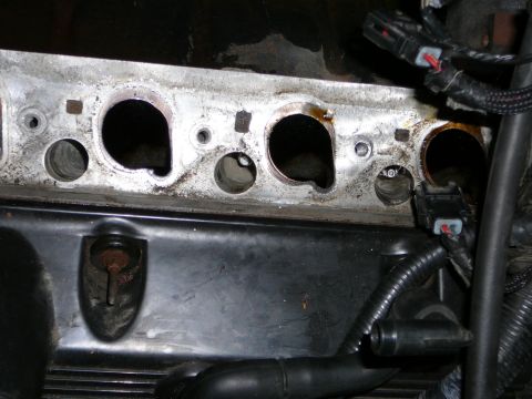 1997 Mercury Grand Marquis - Close-up of an aluminum cylinder head's intake face with the manifold off, showing three D-shaped intake ports, carbon staining, coolant cr…