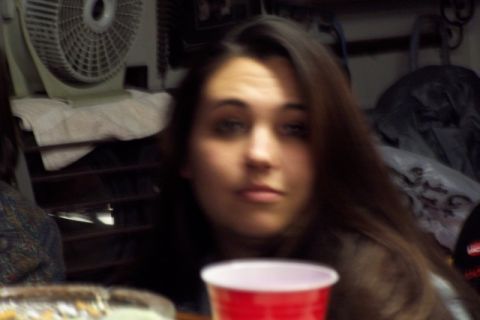 1990 Ford Bronco - A woman is captured in a close-up shot, with a red cup and a fan visible in the background.