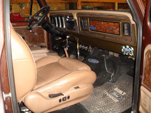 1979 Ford F-150 - The interior of a 1979 Ford F-150 features tan seats, wood grain trim on the dashboard, and Ford-branded floor mats.