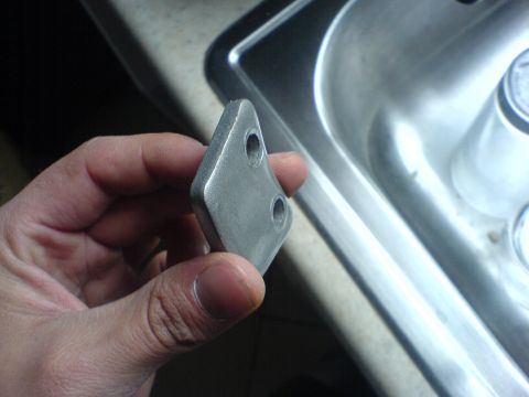 2005 Dodge SRT-4 - A person holds a metal component with two bolt holes, possibly for a vehicle repair.