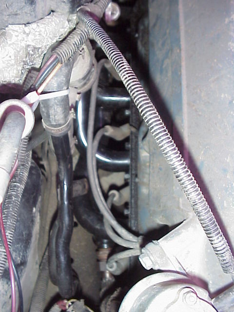 1989 Ford Bronco - Close-up view of engine compartment components, including exhaust headers and various hoses.