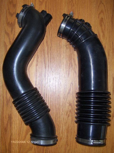 2004 Ford Crown Victoria - Two black rubber air intake hoses are displayed on a wooden surface, with a timestamp visible in the lower left corner.