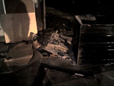 1987 Ford Bronco - A pile of broken materials and trash sits on the ground next to a large, dark dumpster.