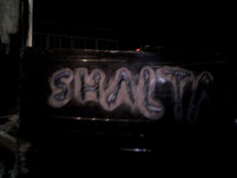 1987 Ford Bronco - Graffiti covers the side of a dark vehicle, obscuring any identifying marks.