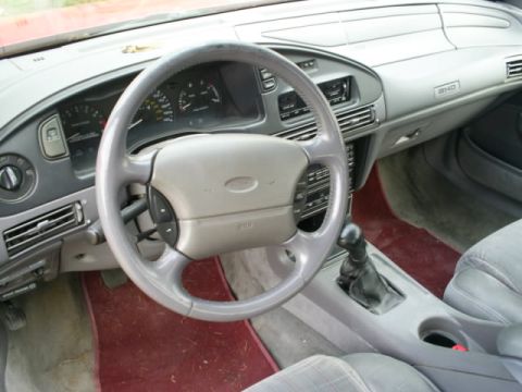 1995 Ford Taurus - The interior of a car, the dashboard, steering wheel, and gear shifter. A 'SHO' badge is visible on the dashboard.