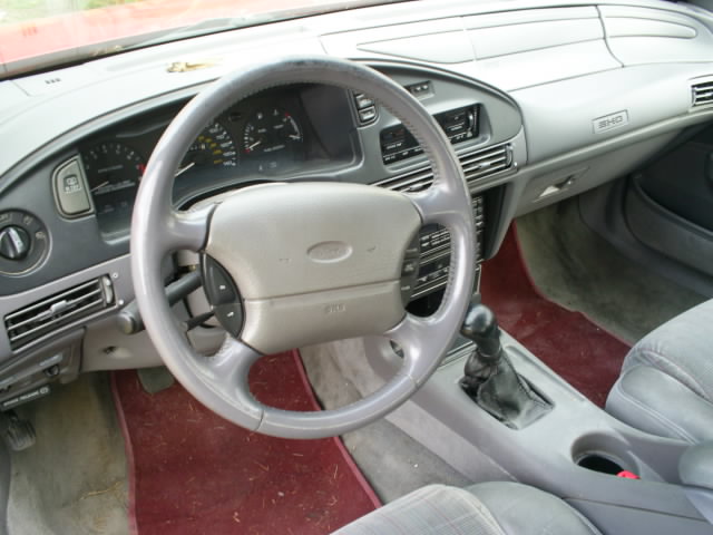 Interior shot of a car's dashboard, steering wheel, and center console. The badge on the dash says SHO