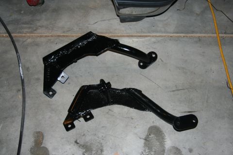 1992 Ford Bronco - Two newly painted metal brackets are laid out on a concrete surface, possibly for installation.