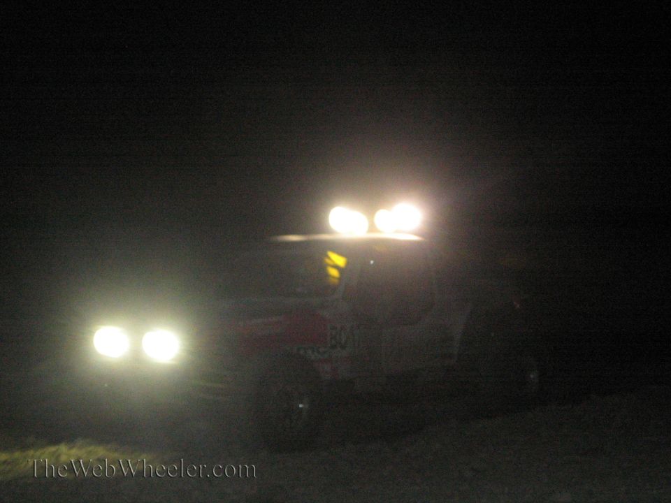 Off-road race truck with roof light bar and headlights at night in the desert