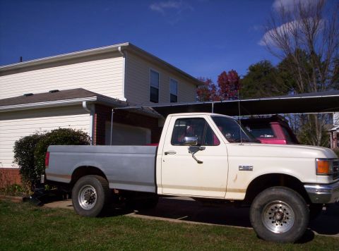 1995 Ford Bronco - A white pickup truck with a gray bed is parked in front of a house.