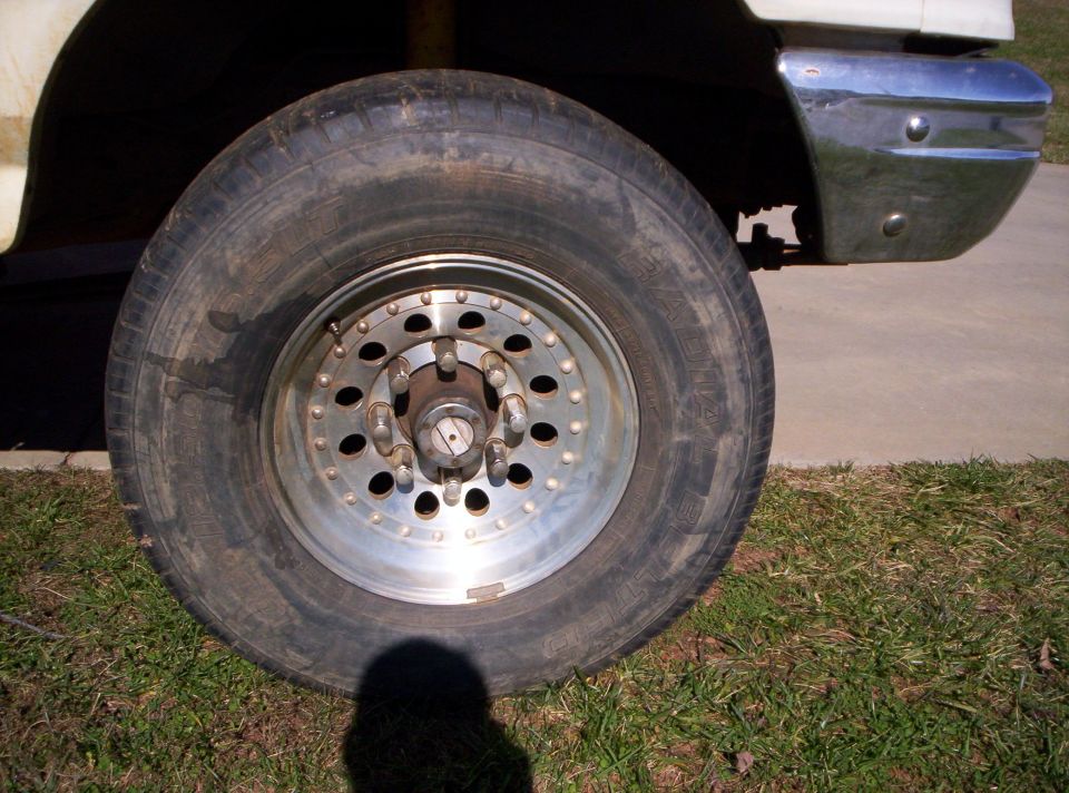 Close-up of a large truck wheel with a chrome bumper visible above it