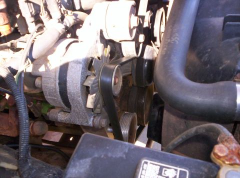 1995 Ford Bronco - Close-up of the front accessory drive on a truck engine, showing the alternator, serpentine belt routing over the idler and tensioner pulle…