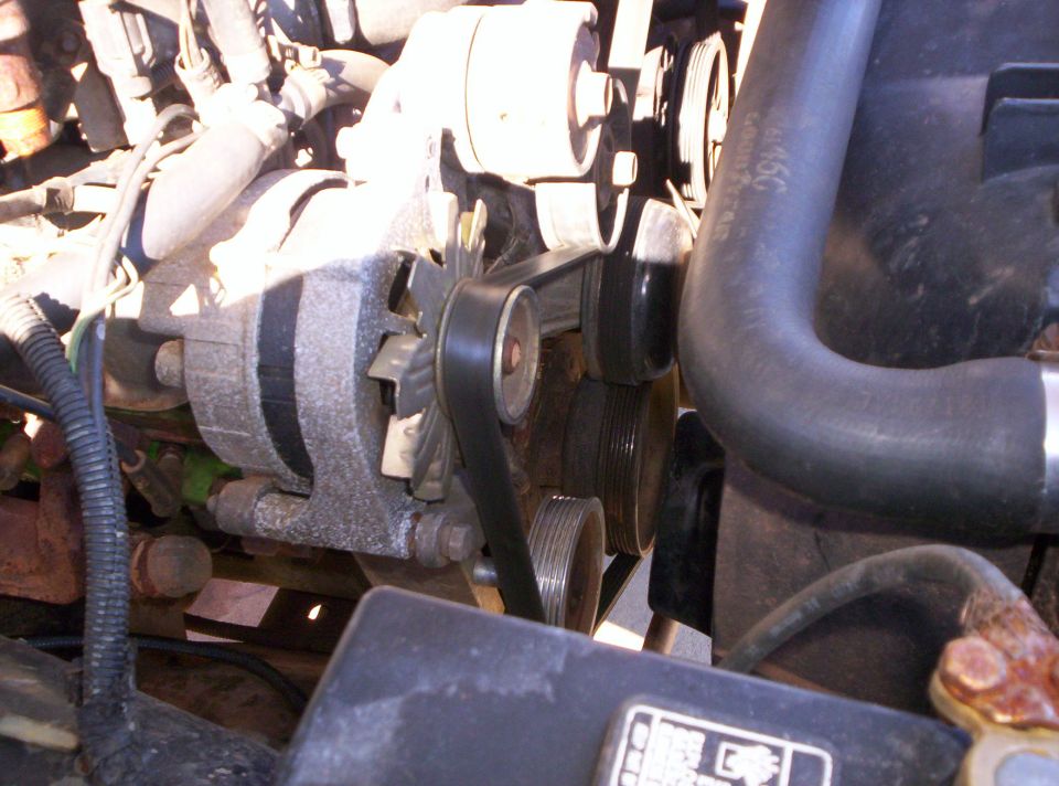 Alternator and serpentine belt with idler and tensioner pulleys on truck engine