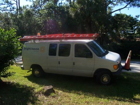1994 Ford Probe - A white van with a ladder rack on top and 'bright house' branding on the side is parked on a grassy area.