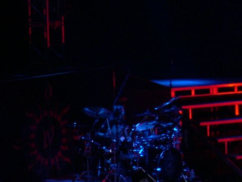 1997 Ford Probe - A drum set is illuminated by blue lights on a stage with red structural lighting in the background.