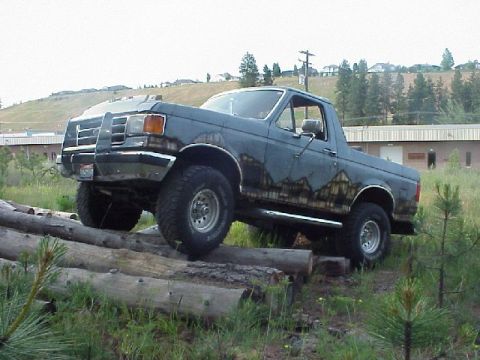 1989 Ford Bronco - This Ford Bronco is navigating an obstacle course of logs in a grassy, hilly area.