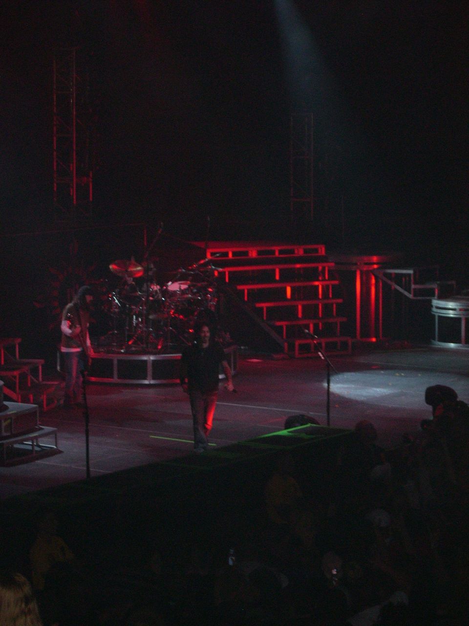 Stage setup with drum kit, stairs, and people on a dimly lit stage