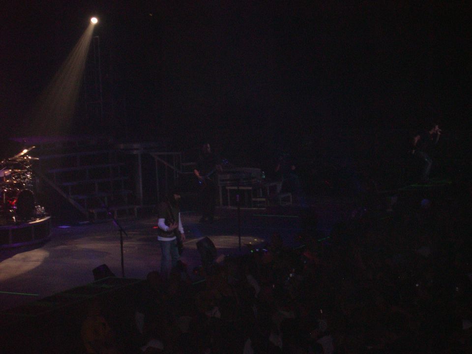 Stage with band performing under a spotlight, drum set visible on the left
