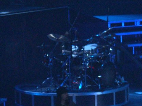 1997 Ford Probe - A drum kit is set up on a stage, illuminated by blue lights, suggesting a live performance.