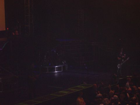 1997 Ford Probe - A band performs live on stage in front of an audience, with stage lighting and equipment visible.