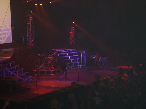 1997 Ford Probe - A band performs on a concert stage with lighting and a drum set, while an audience watches.