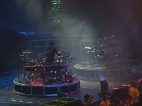 1997 Ford Probe - A performer stands behind a large drum set on a concert stage, with another drum set visible in the background.