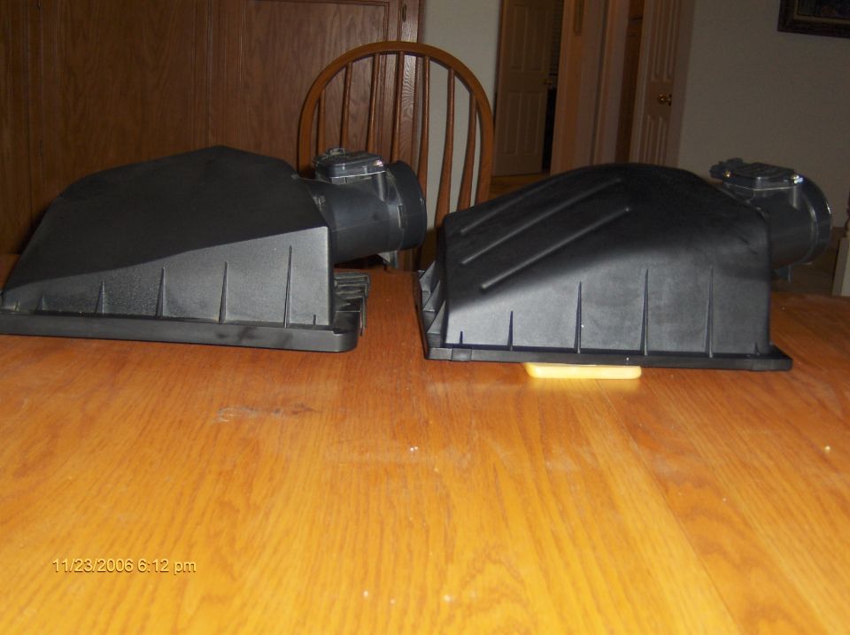 Two black plastic air intake boxes on a wooden table