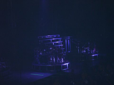 1997 Ford Probe - Stage setup with drum kits, illuminated by blue lights. Includes SUPERMOTORS.NET watermark.