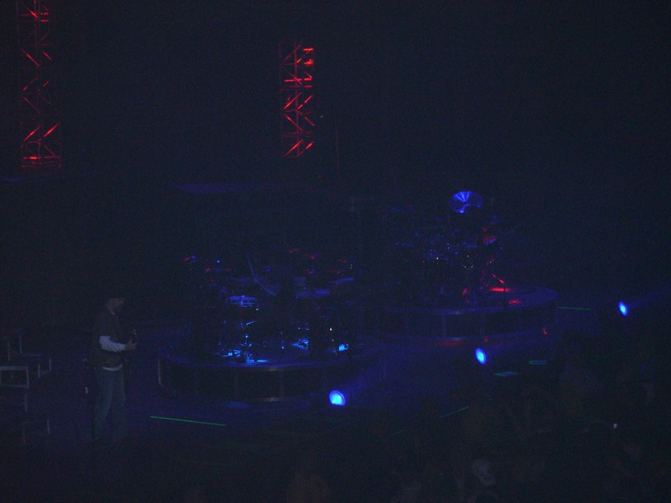 Stage setup with drum kit, lighting trusses, and blue stage lights