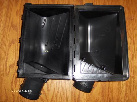 2004 Ford Crown Victoria - This is an open air cleaner housing, likely for a vehicle, shown on a wooden surface.