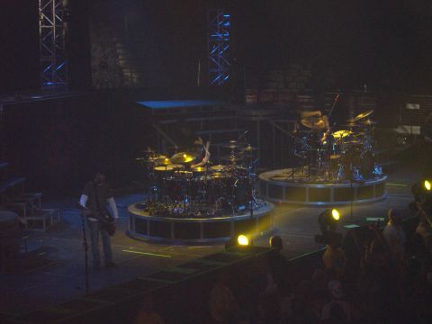 1997 Ford Probe - A live music performance is underway with multiple drum sets and performers on a dimly lit stage.