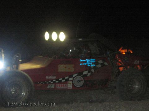 1990 Ford Bronco - red off-road race buggy numbered 1565 with three roof-mounted lights and checkered graphics sits in the dark desert.