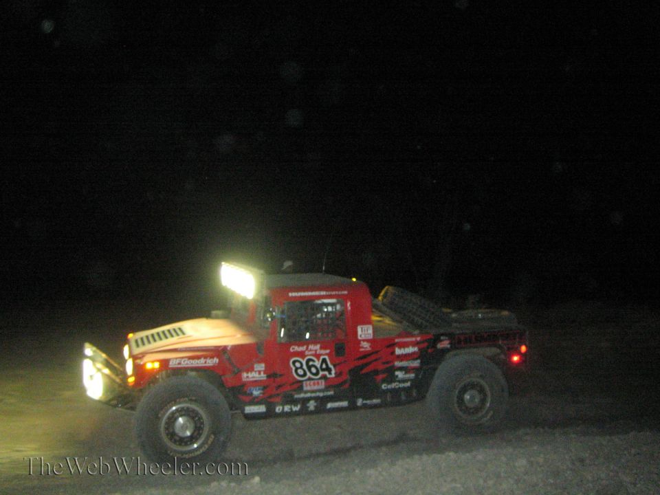 Red Hummer-style off-road race truck number 864 at night