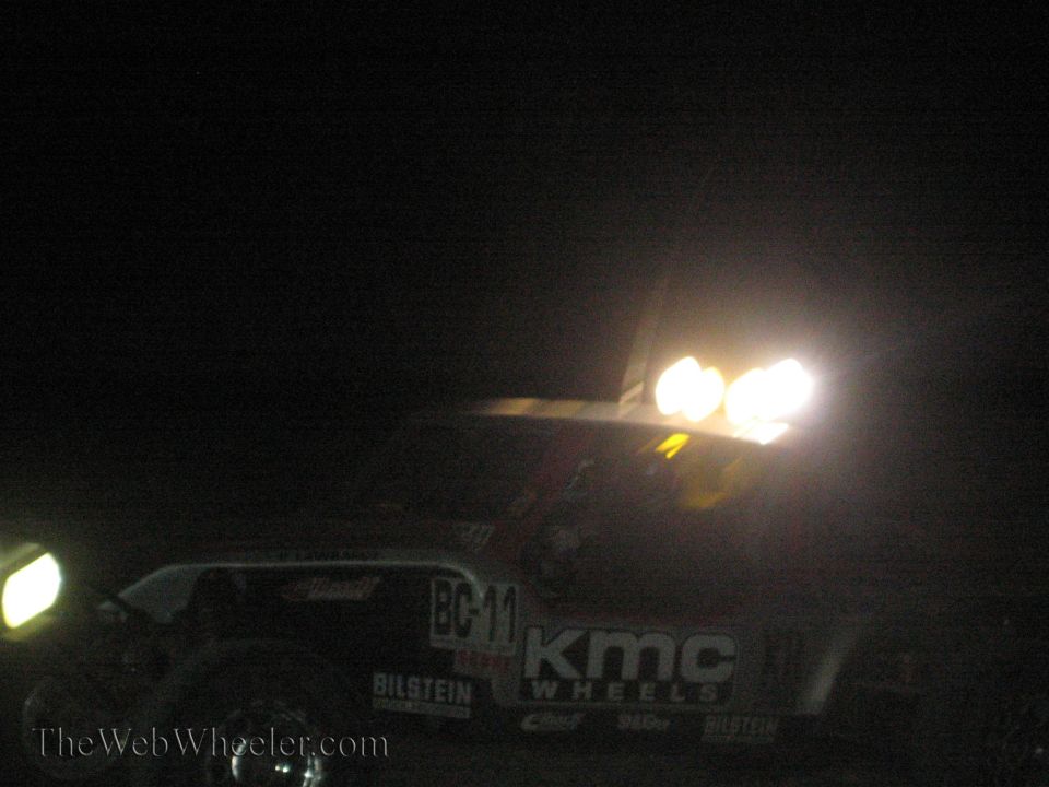 Off-road race vehicle with KMC Wheels decals and bright lights at night