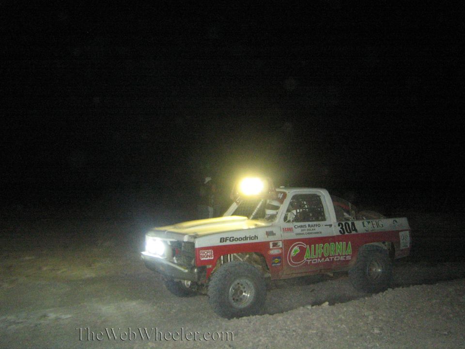 Red off-road race truck number 304 with California Tomatoes livery at night