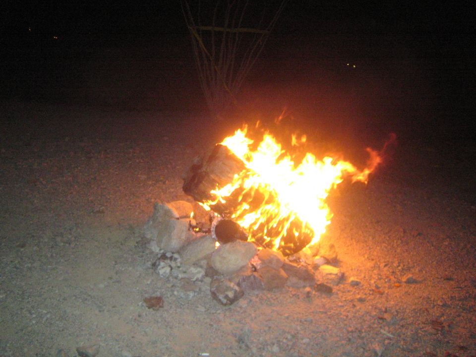 Large campfire ringed with rocks in the desert at night