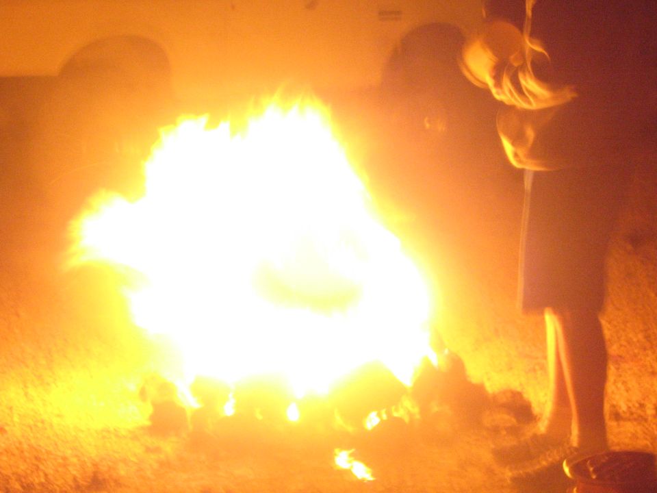 Bright blazing campfire with a person standing at the right at night