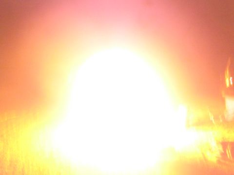 1990 Ford Bronco - intensely bright, overexposed glow fills the frame from a campfire blaze in the dark at night.