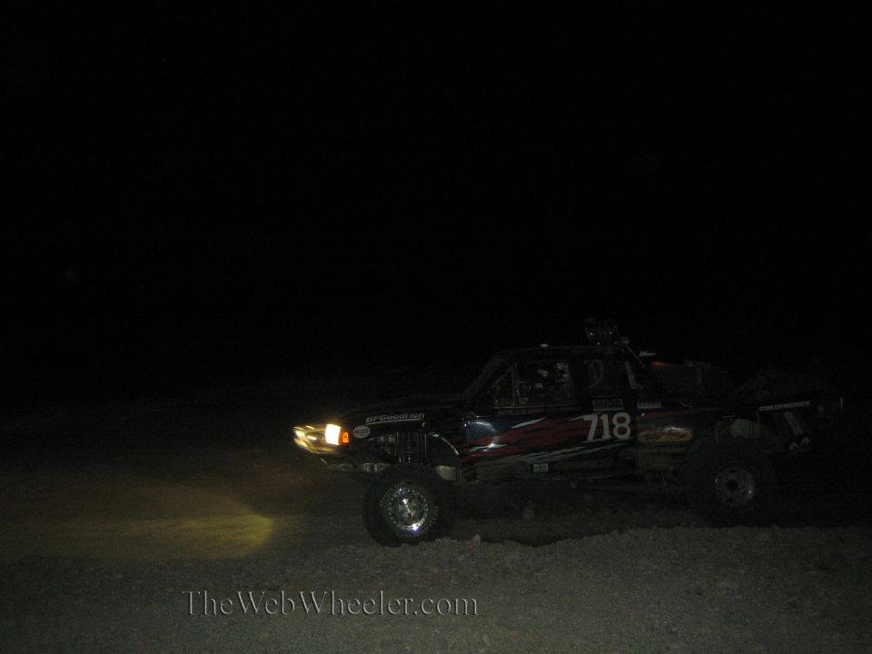 Off-road race truck number 718 with headlights on at night