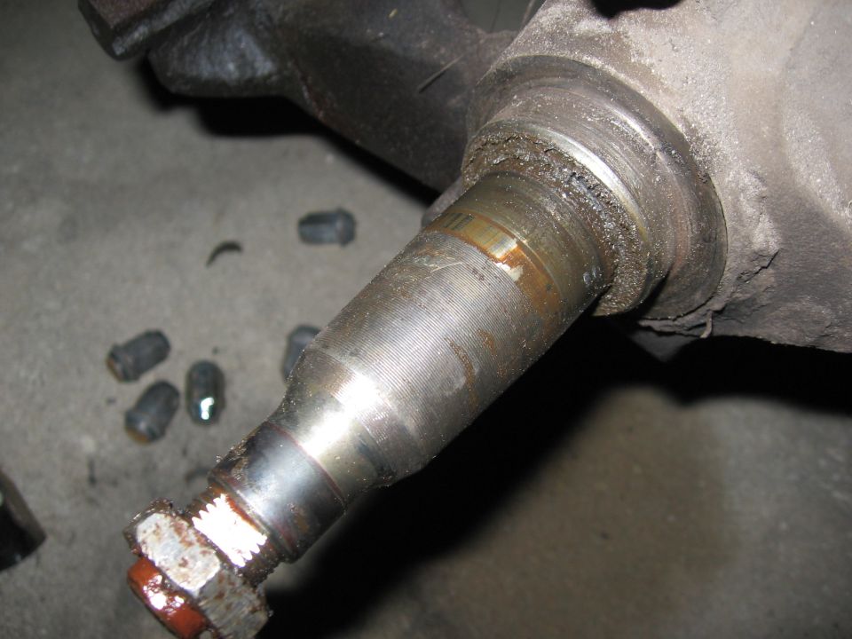 Close-up of a greasy ball joint with a nut and cotter pin visible
