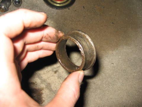 1974 Ford F-100 - A close-up shows a worn metal bearing sleeve being held by a hand, likely for inspection or replacement.