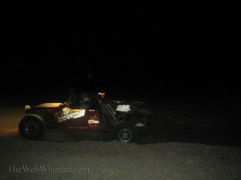 1990 Ford Bronco - dark off-road race vehicle with Jeffries and BFGoodrich decals drives across the desert at night.