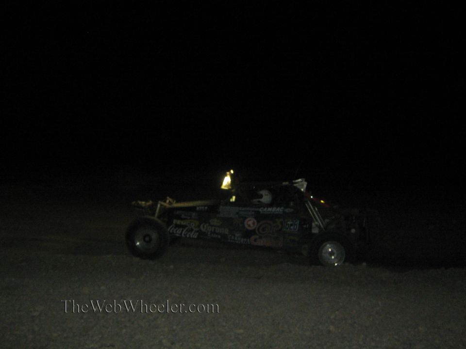 Off-road buggy with beverage sponsor decals racing at night