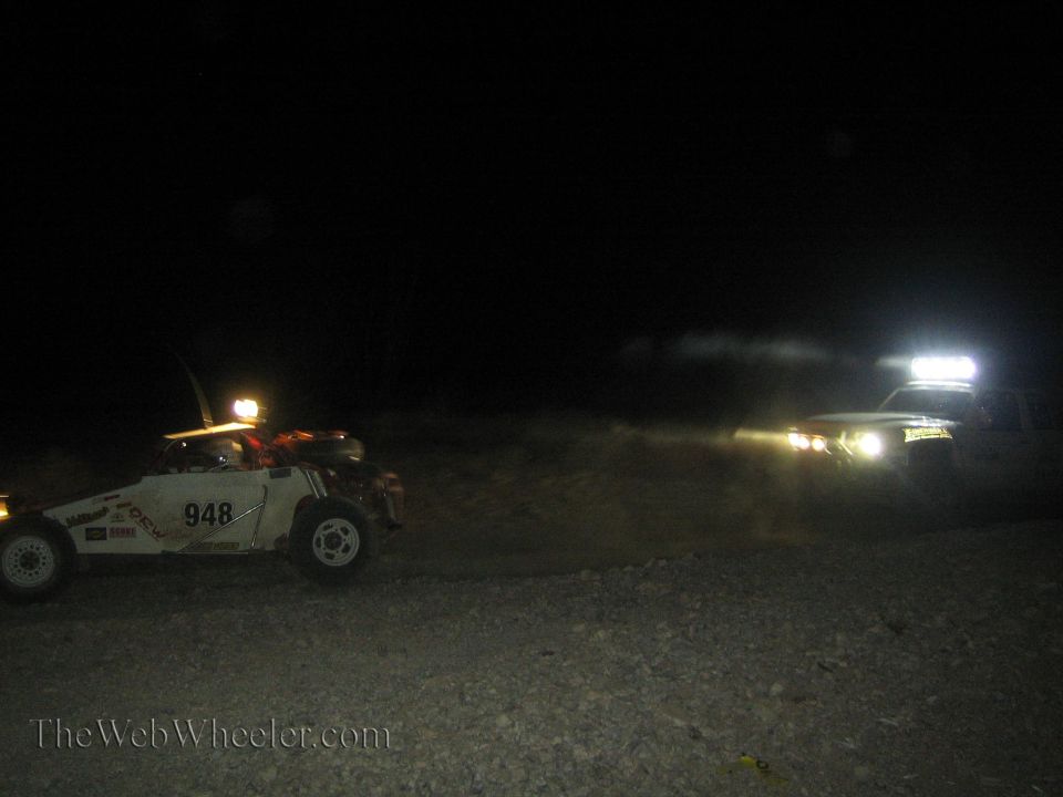 Two off-road race vehicles including number 948 at night