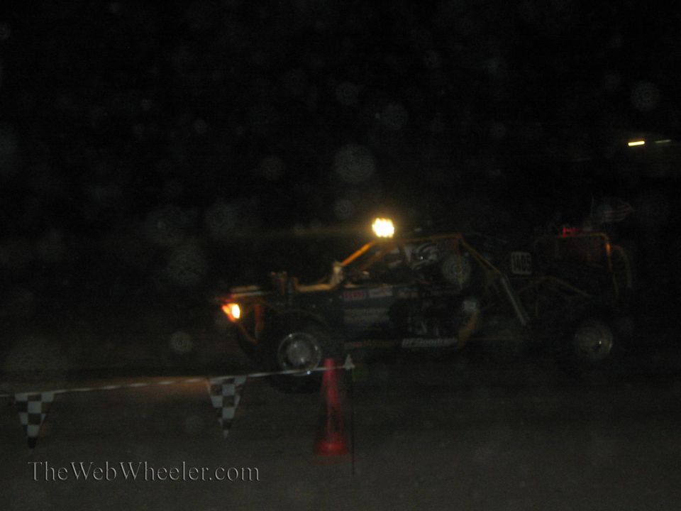 Off-road race buggy passing course barrier at night