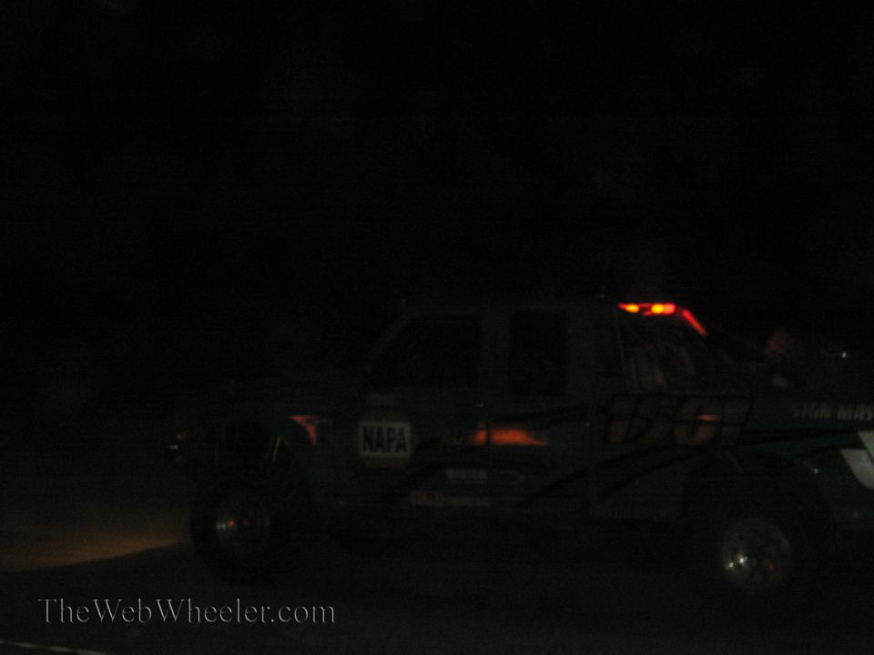 Lifted pickup truck with roof-mounted lights at a night off-road race